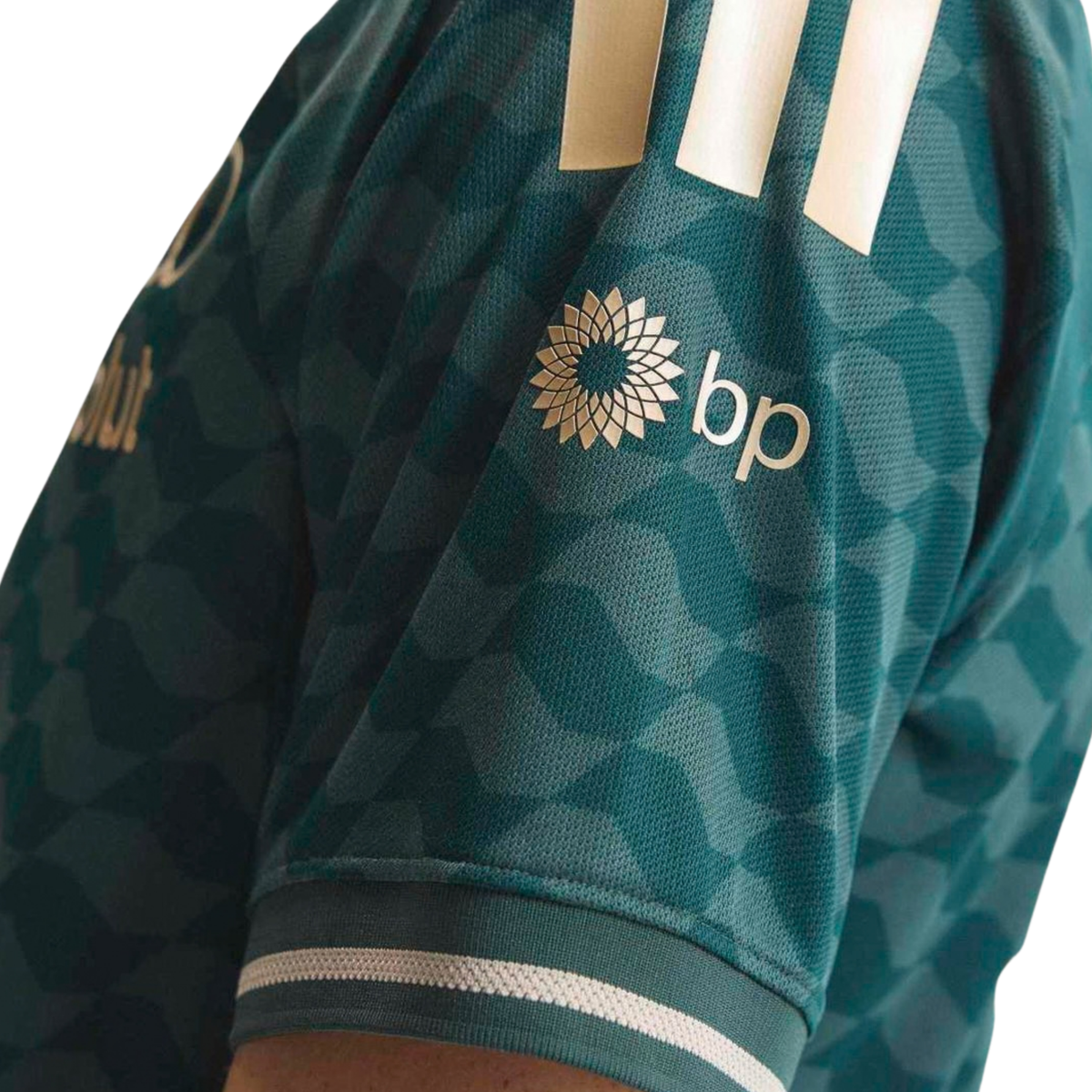 A green and gold Audi F1 Team 2026 t-shirt featuring an all-over geometric pattern, a crew neck with gold trim, and official partner logos including Audi and Revolut across the chest.