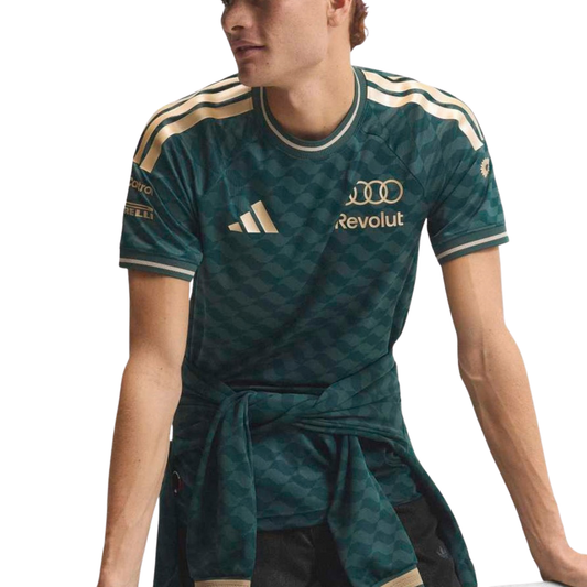 A green and gold Audi F1 Team 2026 t-shirt featuring an all-over geometric pattern, a crew neck with gold trim, and official partner logos including Audi and Revolut across the chest.