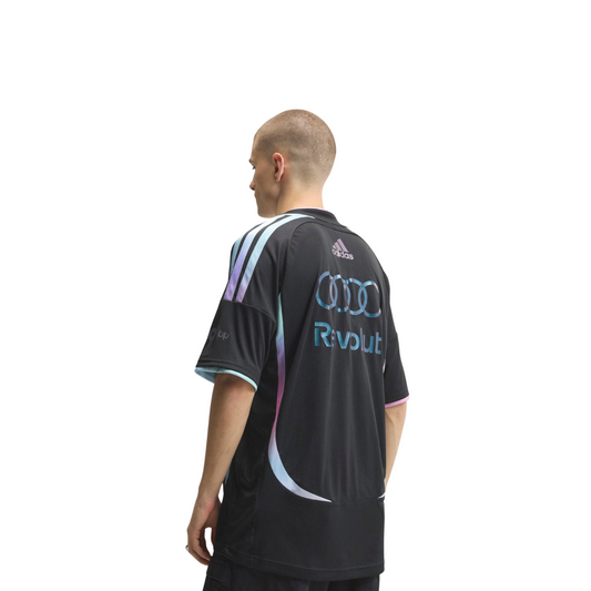 A black, pink, and light blue Audi F1 Team 2026 t-shirt featuring a crew neck with pink and light blue trim, curved gradient side panels, and official partner logos including Adidas and Revolut across the chest.
