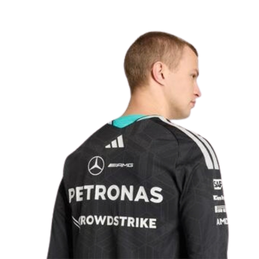 A black Mercedes-AMG Petronas 2026 team long-sleeve t-shirt featuring an all-over tonal geometric pattern, a V-neck collar with white shoulder stripes and vibrant teal inner trim, and official partner logos including Mercedes-AMG, Petronas, and UBS across the chest.