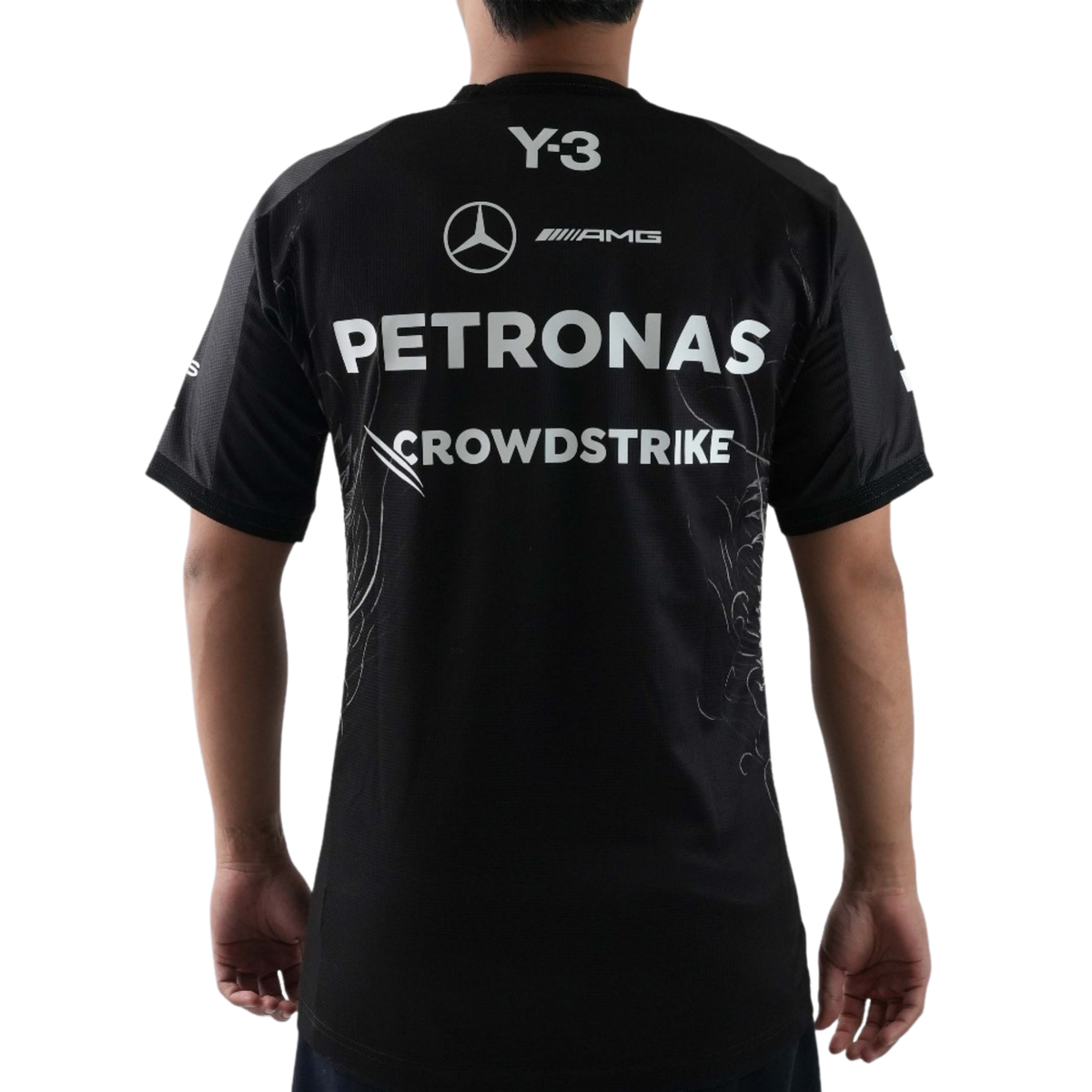 A special edition black Mercedes-AMG Petronas 2026 team t-shirt featuring a dynamic full-body crouching wolf graphic spanning the lower front and side, white shoulder stripes, and official partner logos including Mercedes-AMG, Petronas, and Y-3 across the chest.