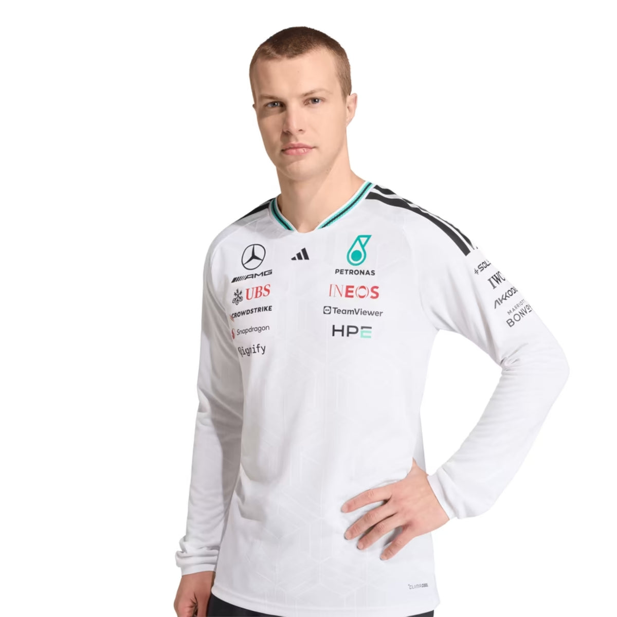A white Mercedes-AMG Petronas 2026 team long-sleeve t-shirt featuring a V-neck collar with black shoulder stripes and teal inner trim, ribbed cuffs with contrast striping, and official partner logos including Mercedes-AMG, Petronas, and UBS across the chest.