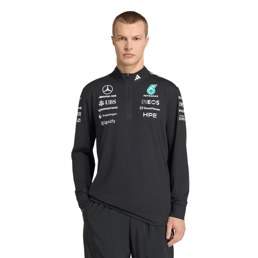 Model wearing a black Mercedes-AMG Petronas F1 2026 team 1/4-zip sweatshirt with sponsor logos including Adidas, UBS, and CrowdStrike