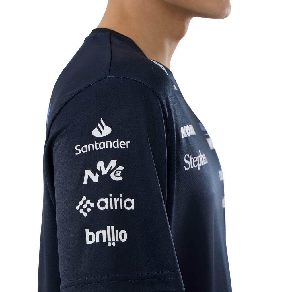 A navy blue and royal blue Williams Racing 2026 replica tech t-shirt featuring a crew neck, dynamic brushstroke graphics on the lower front, and official partner logos including Atlassian Williams F1 Team, Komatsu, Gulf, and Duracell across the chest.
