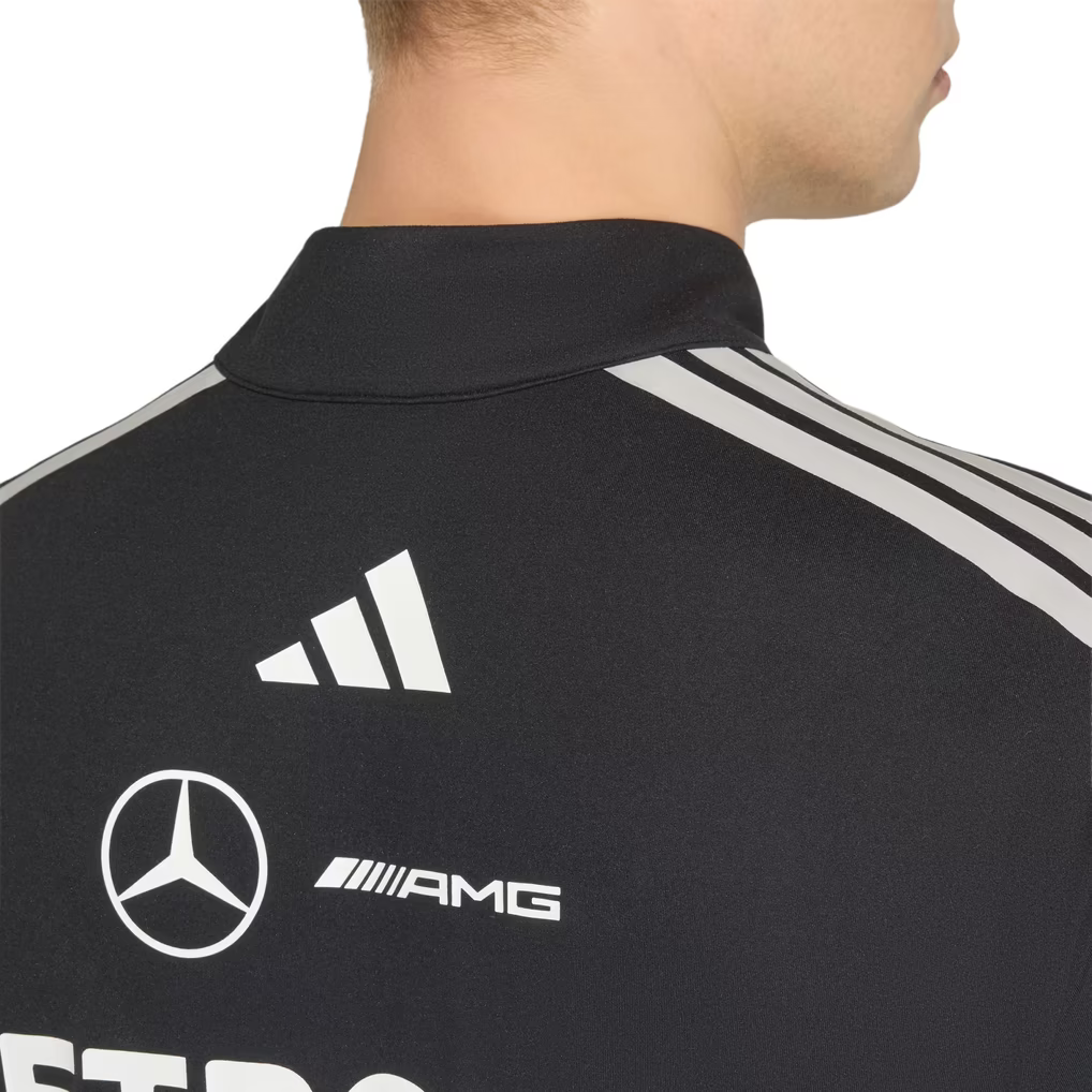 Model wearing a black Mercedes-AMG Petronas F1 2026 team 1/4-zip sweatshirt with sponsor logos including Adidas, UBS, and CrowdStrike