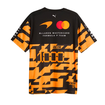 A black, orange, and charcoal McLaren F1 special edition 1000th race t-shirt featuring a crew neck, a bold geometric graphic pattern across the lower half, and official partner logos including Android, Dell Technologies, OKX, and DP World on the chest.