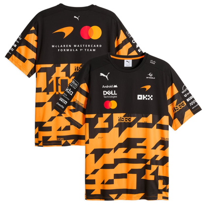 A black, orange, and charcoal McLaren F1 special edition 1000th race t-shirt featuring a crew neck, a bold geometric graphic pattern across the lower half, and official partner logos including Android, Dell Technologies, OKX, and DP World on the chest.