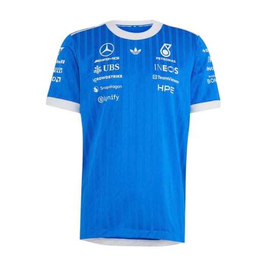 A blue and white Mercedes-AMG Petronas 2026 blue edition t-shirt featuring an all-over vertical pinstripe pattern, a white crew neck and sleeve cuffs, and official partner logos including Mercedes-AMG, Petronas, and UBS across the chest.