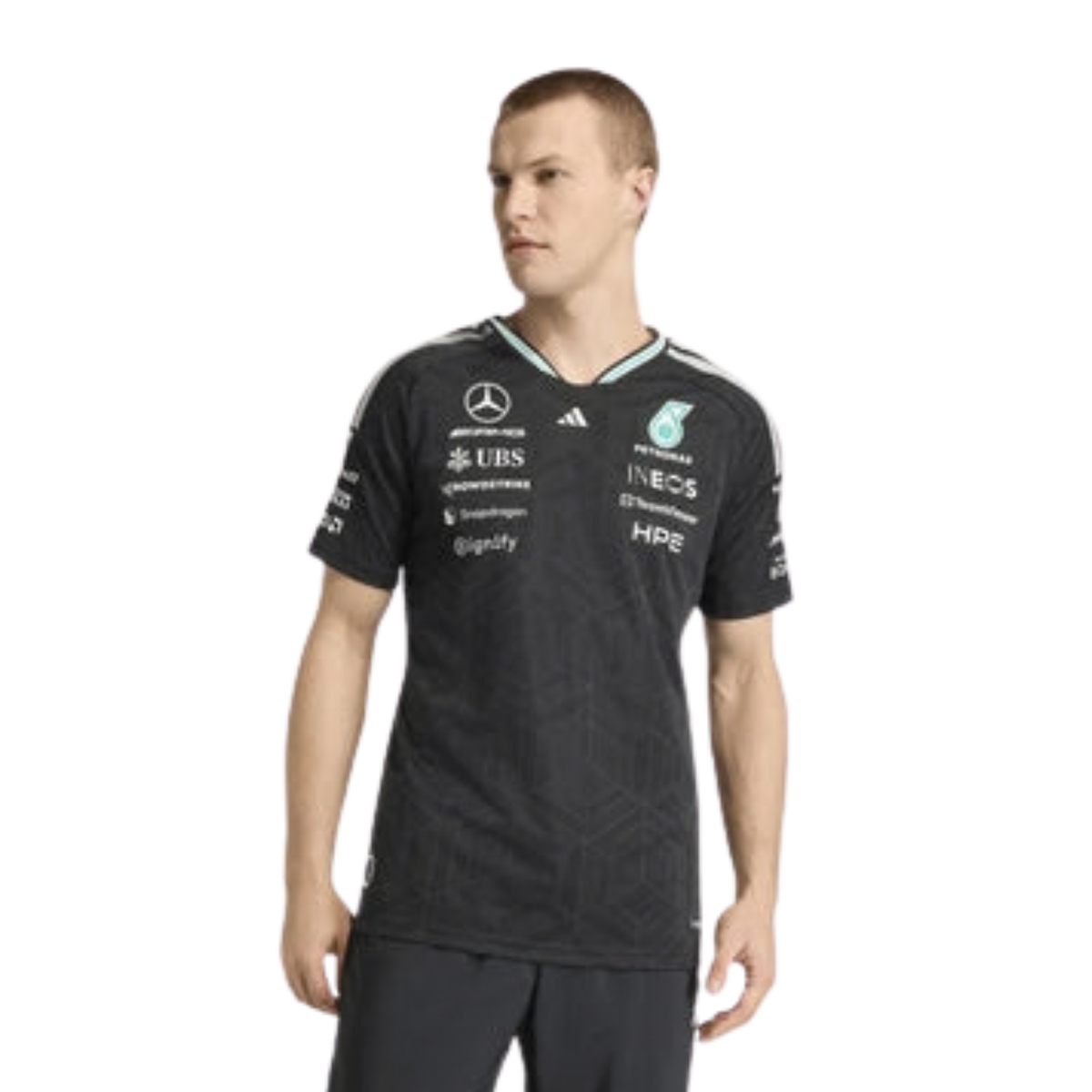 A black Mercedes-AMG Petronas 2026 driver t-shirt featuring an all-over tonal geometric pattern, a V-neck collar with white shoulder stripes and vibrant teal inner trim, and official partner logos including Mercedes-AMG, Petronas, and UBS across the chest.