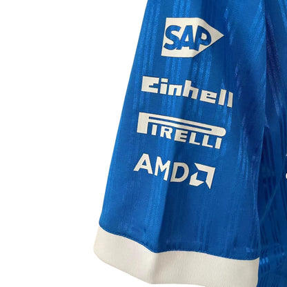 Official Mercedes-AMG Petronas 2026 team polo shirt in blue with a white collar, featuring sponsor logos including INEOS, UBS, and CrowdStrike.