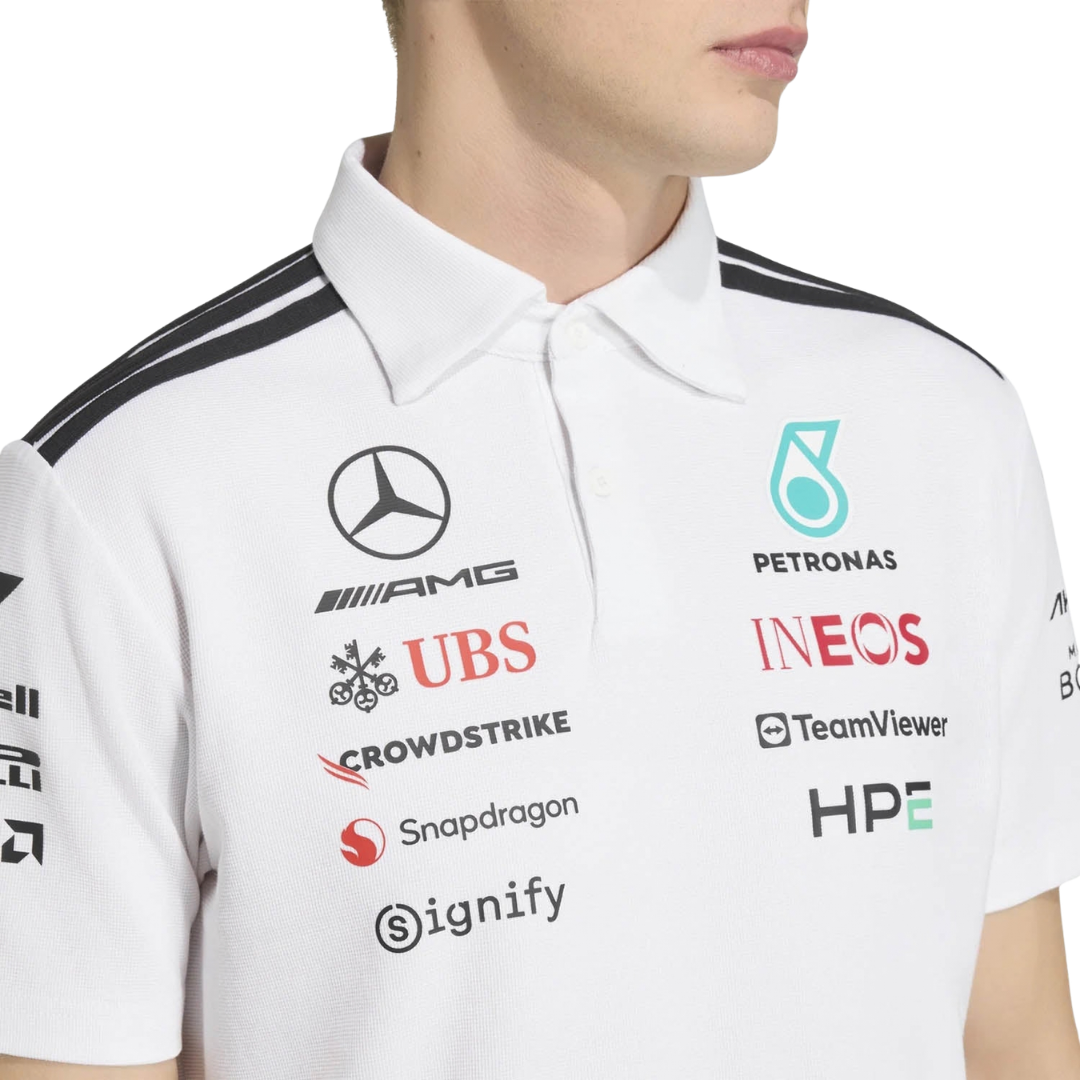 A white Mercedes-AMG Petronas 2026 team polo shirt featuring a classic collar with black shoulder striping, a button placket, and official partner logos including Mercedes-AMG, Petronas, and INEOS across the chest.