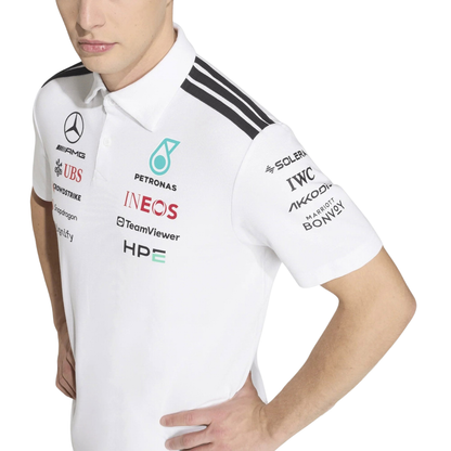 A white Mercedes-AMG Petronas 2026 team polo shirt featuring a classic collar with black shoulder striping, a button placket, and official partner logos including Mercedes-AMG, Petronas, and INEOS across the chest.