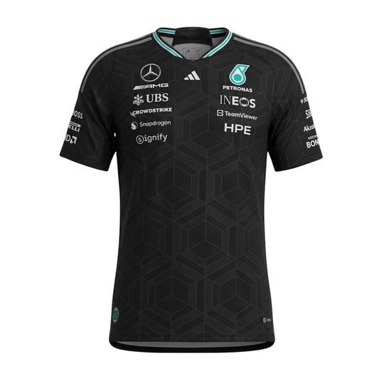A black Mercedes-AMG Petronas F1 2026 team t-shirt featuring a subtle geometric pattern, a crew neck with teal accents, and official partner logos including UBS, Ineos, and CrowdStrike across the chest.