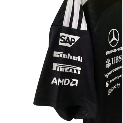 A black Mercedes-AMG Petronas F1 2026 team t-shirt featuring a subtle geometric pattern, a crew neck with teal accents, and official partner logos including UBS, Ineos, and CrowdStrike across the chest.
