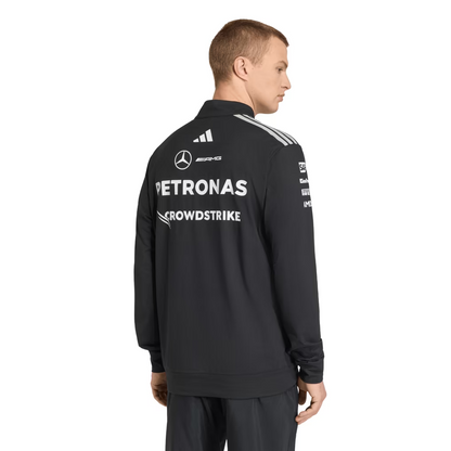 Model wearing a black Mercedes-AMG Petronas F1 2026 team 1/4-zip sweatshirt with sponsor logos including Adidas, UBS, and CrowdStrike