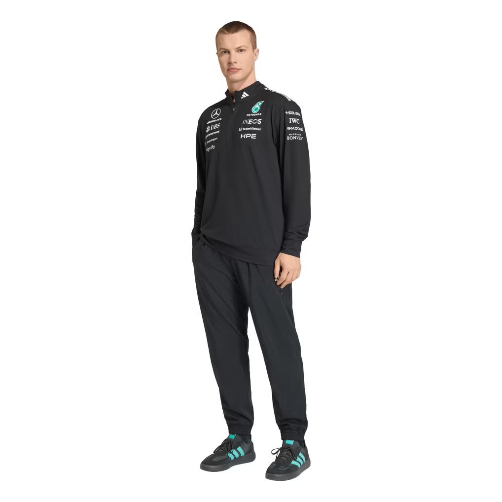 Model wearing a black Mercedes-AMG Petronas F1 2026 team 1/4-zip sweatshirt with sponsor logos including Adidas, UBS, and CrowdStrike